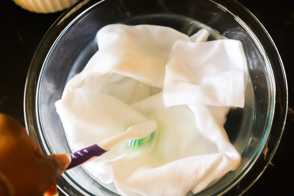 scrubbing olive oil out of clothes with a toothbrush