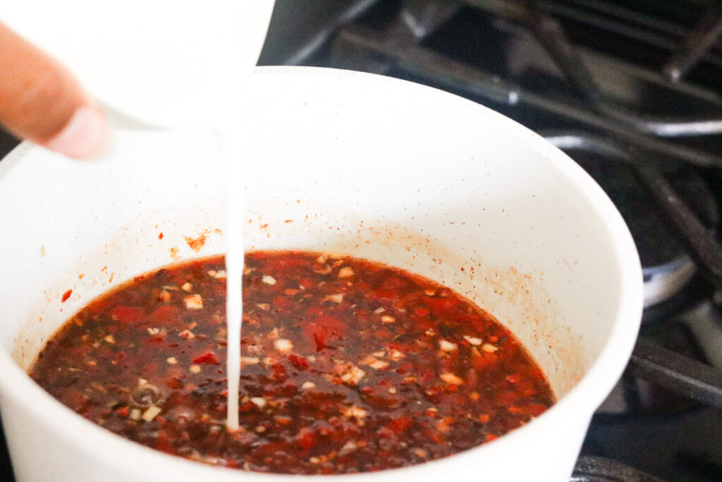pouring cornstarch and water into home made sweet chilli sauce