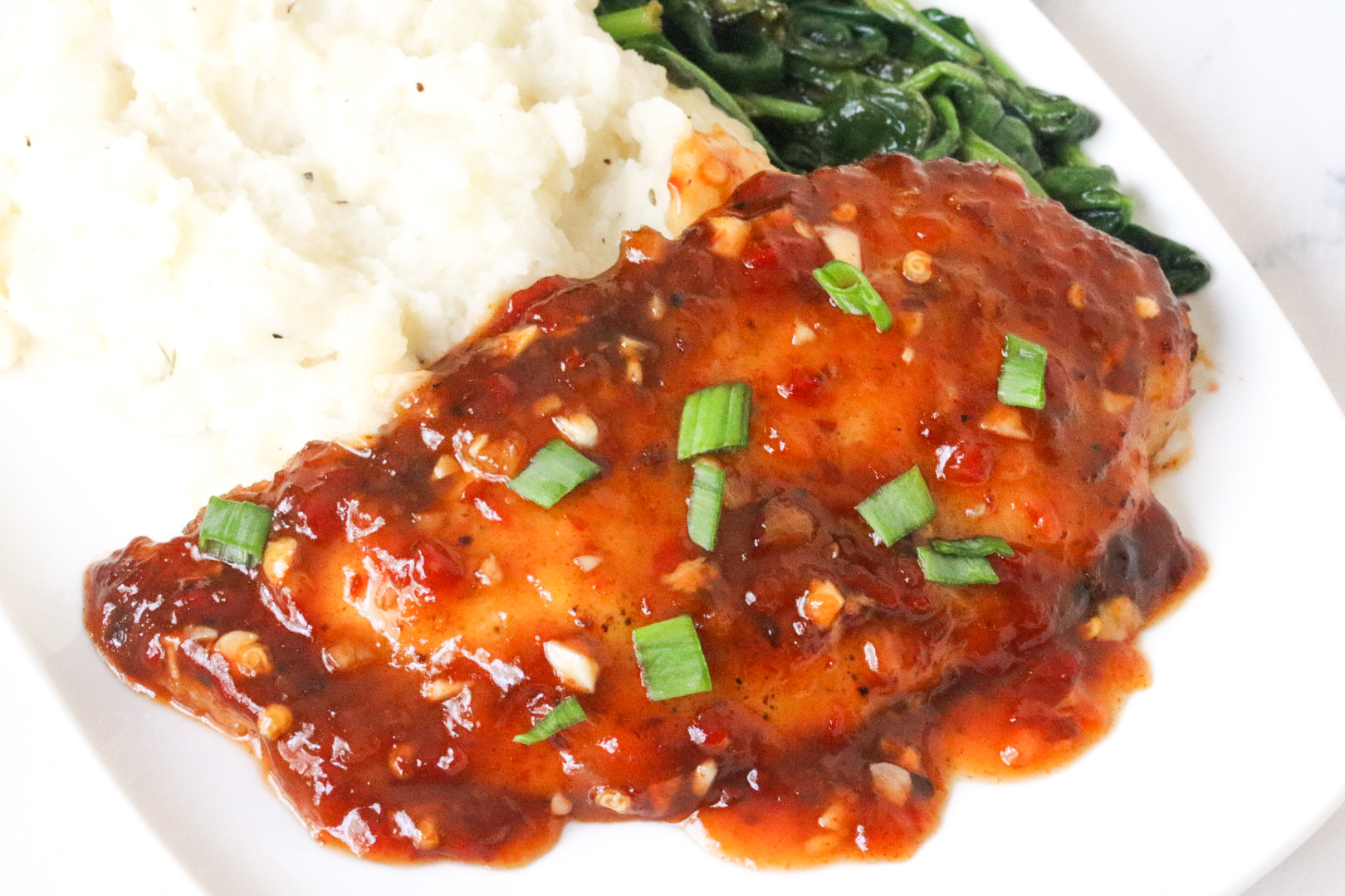chicken sweet chili on plate with spinach and mashed potatoes