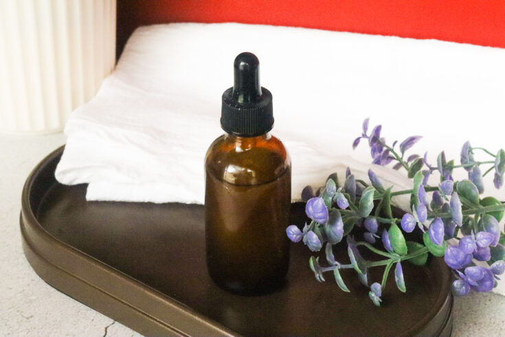 hot oil massage oil on brown tray next to purple plant