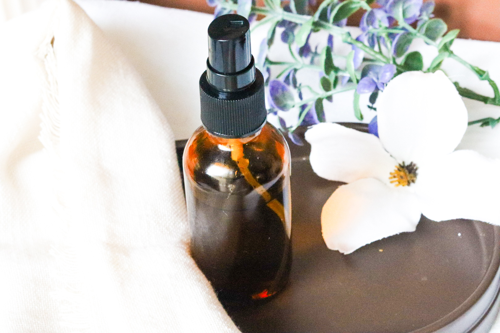 peaceful sleep spray on brown tray next to jasmine flower
