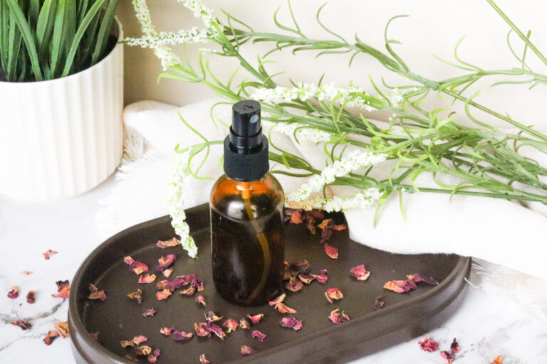 Rose Water Mist Spray on brown tray next to white linen and leaves
