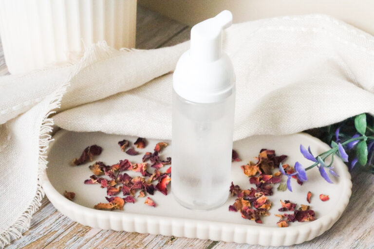 natural feminine wash next to dried rose petals and on a white tray